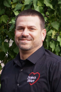 Jim Amaral Staff Photo wearing a black Project Heart button up shirt